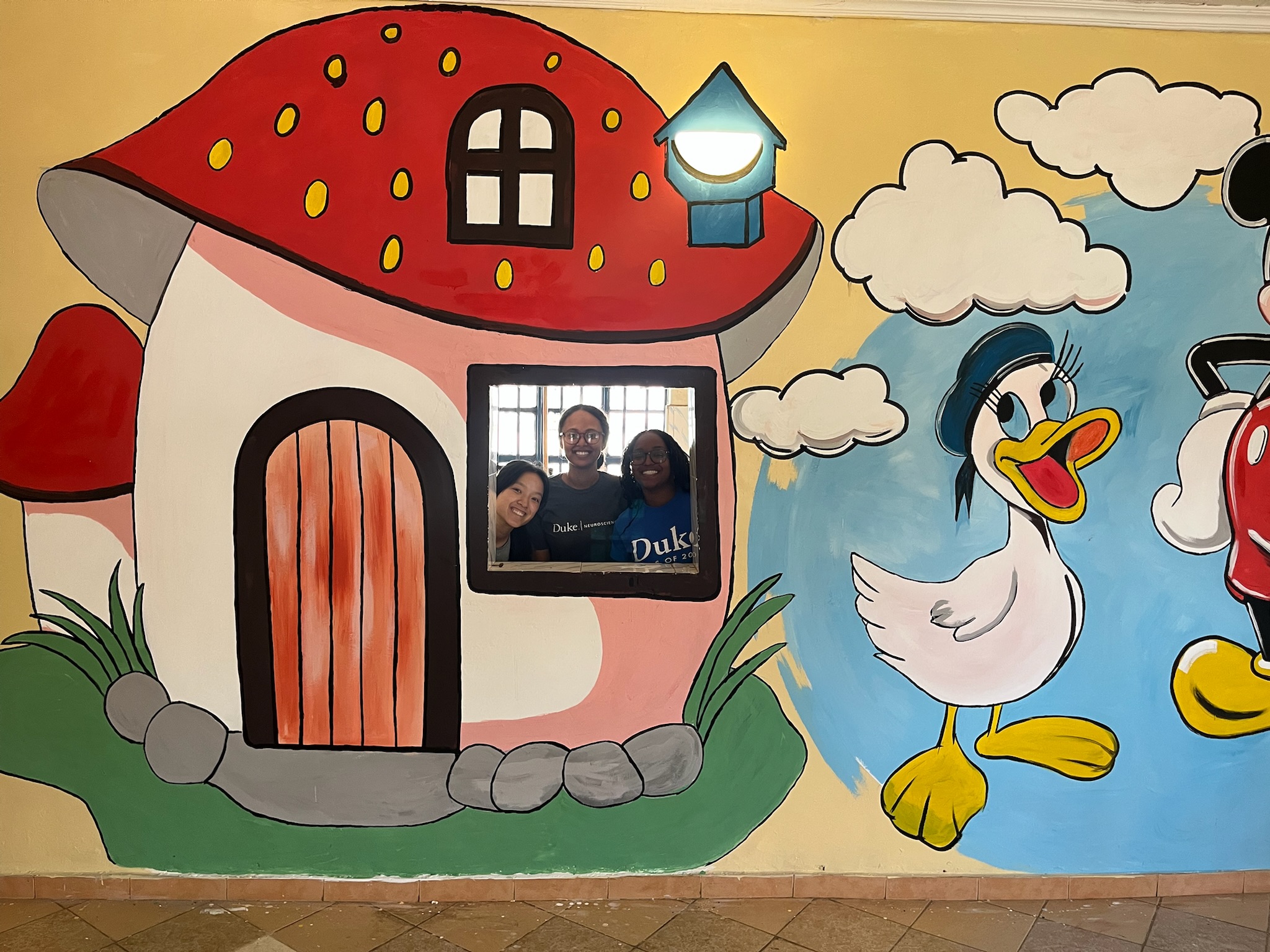 Whimsical wall mural with mushroom house and cartoon characters
