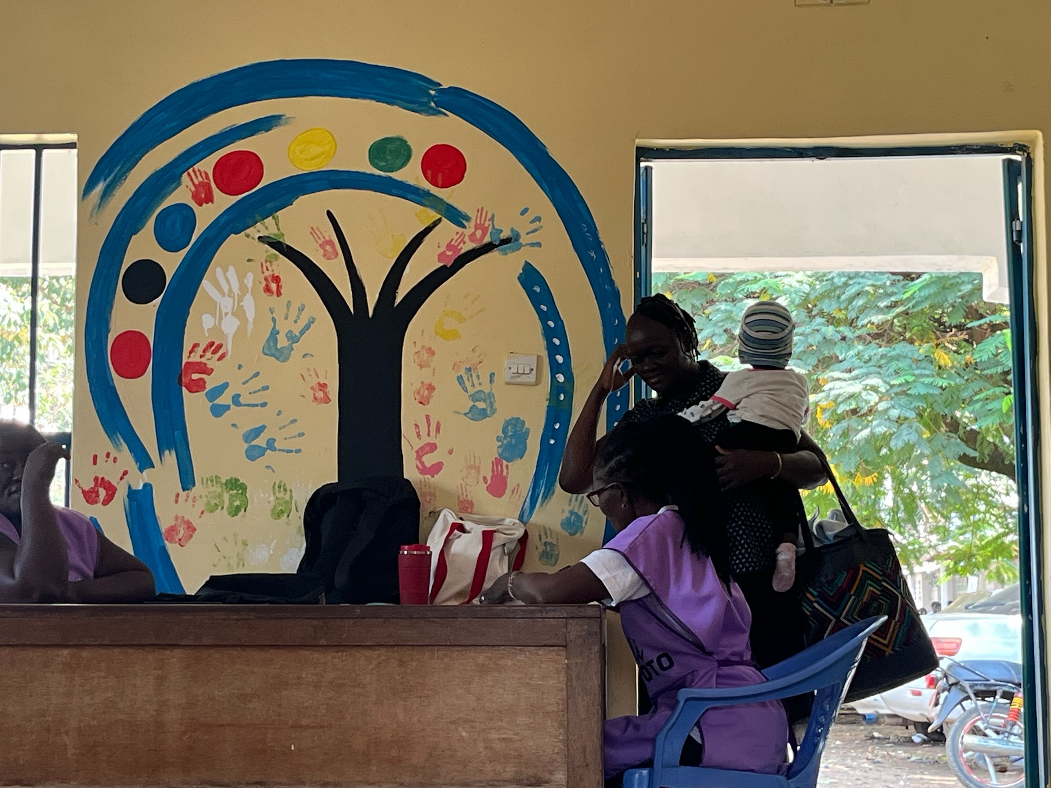 Caregiver with child at the center with handprint tree mural